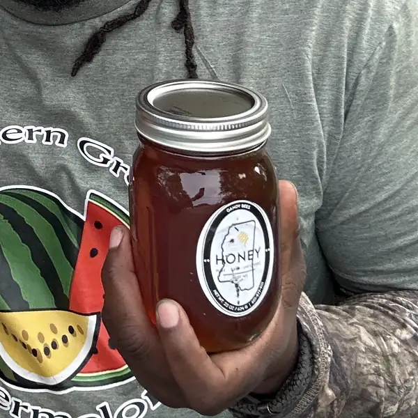 A mason jar of raw Mississippi honey held at the truck